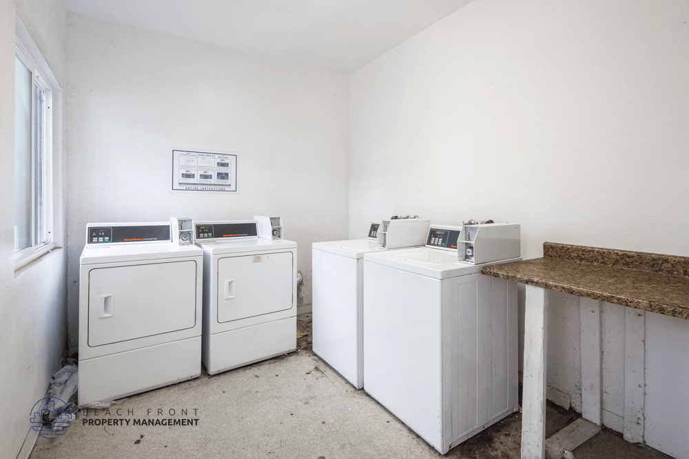 A white room with a brown counter and a fridge on the left.